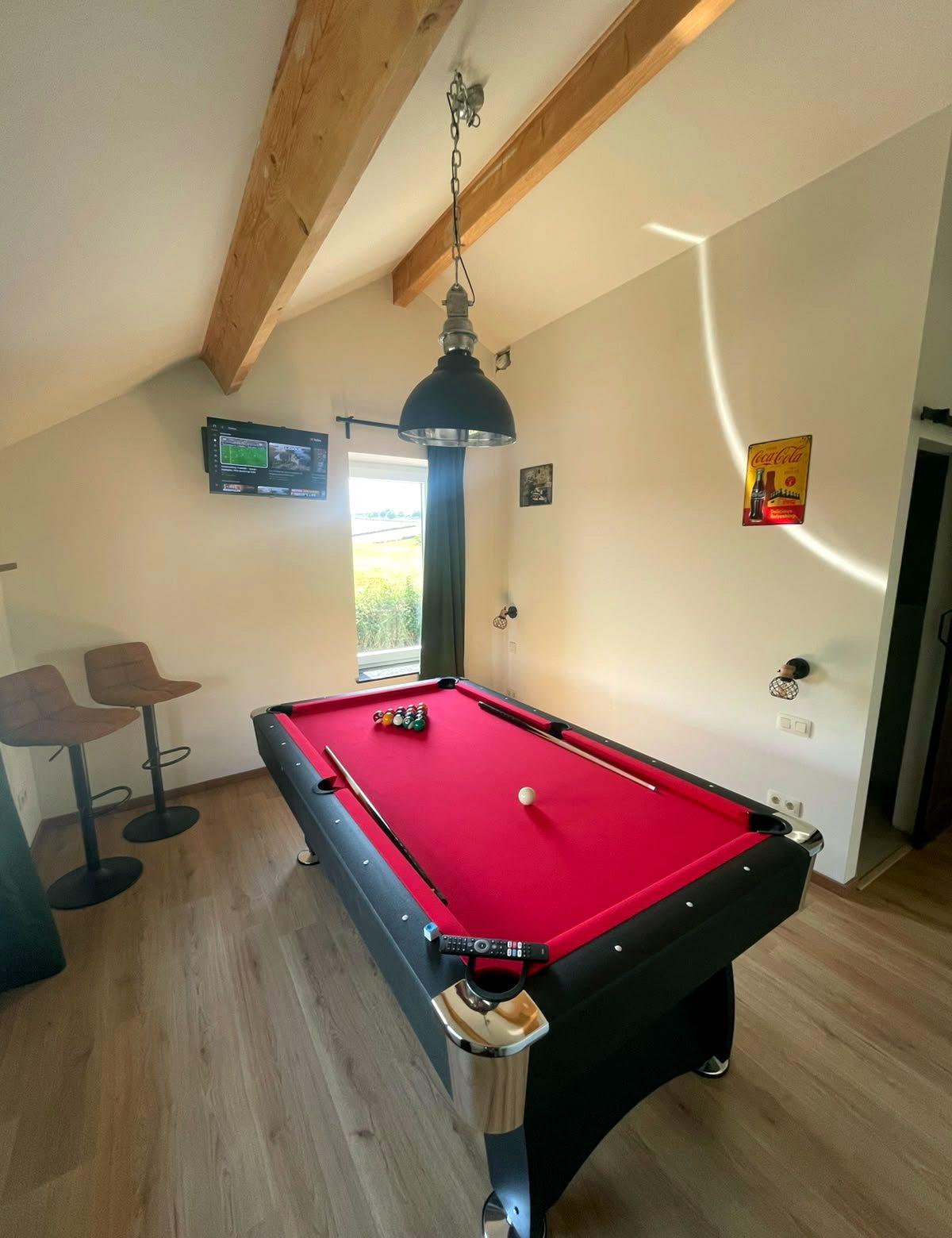 Biljarttafel onder oude balken in de spelkamer van de vakantiewoning in Teuven
