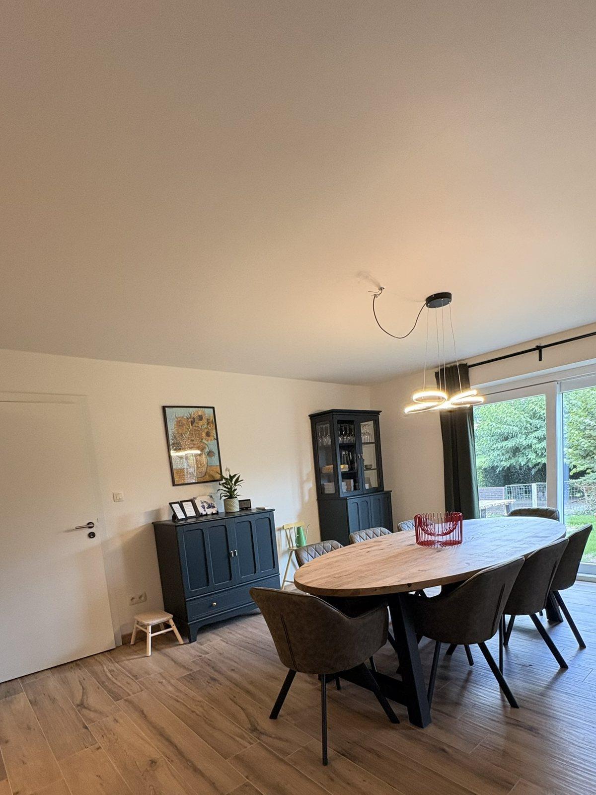 Ovale eettafel voor acht met blauwe kast en schuifraam naar de tuin, vakantiewoning Maison Campagnard in Teuven