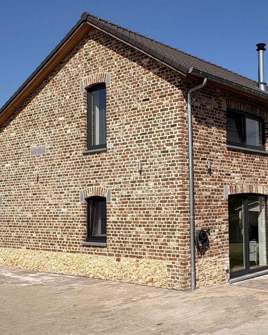 Gerenoveerde hoeve Maison Campagnard in Teuven: bakstenen gevel met natuurstenen plint en glazen inkomdeur, vakantiewoning in de Voerstreek