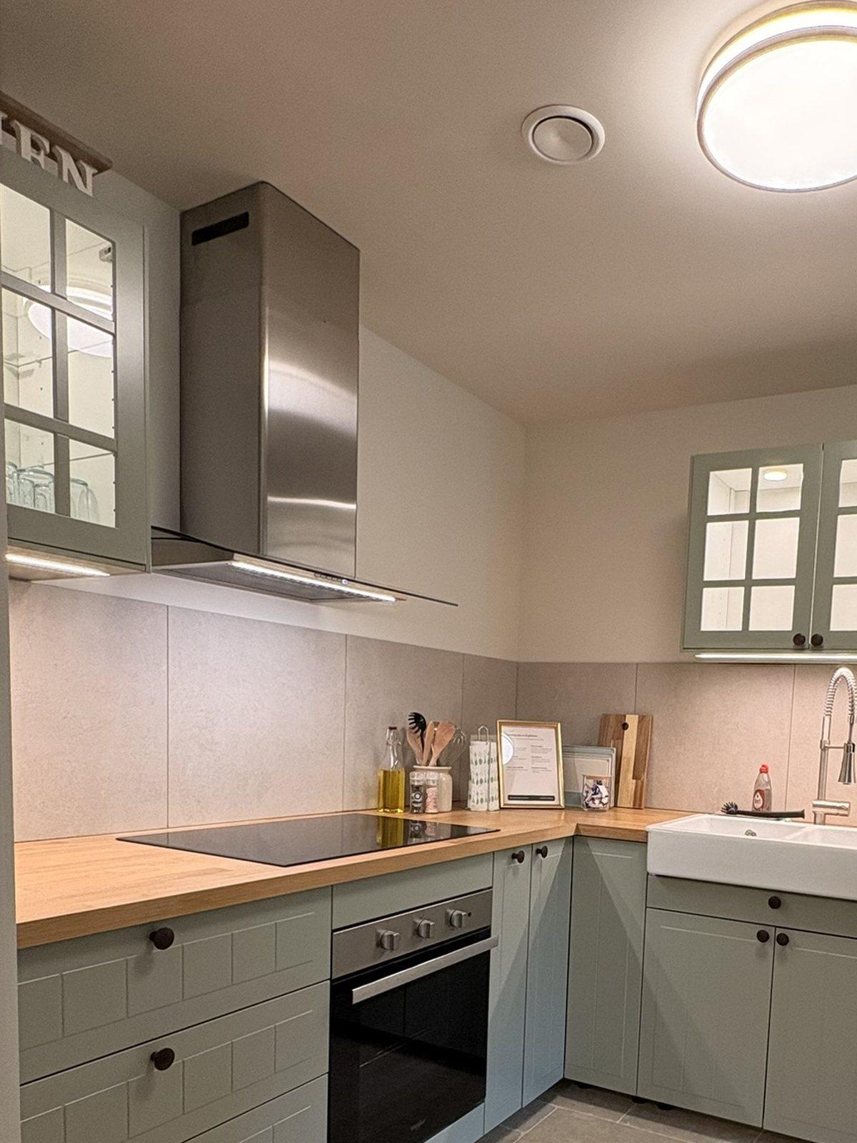 Keuken met inductiekookplaat, oven, dampkap en houten werkblad in vakantiewoning Maison Campagnard, Teuven