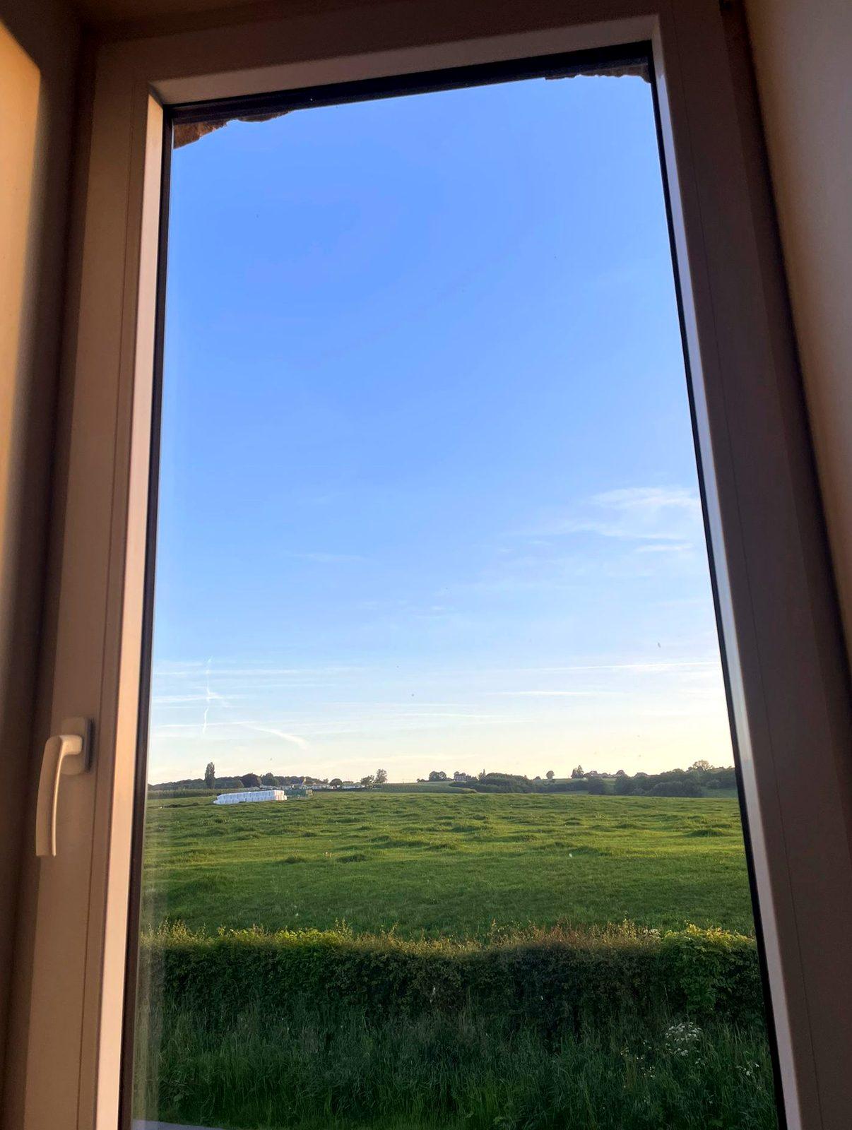 Uitzicht vanuit het slaapkamerraam over de weilanden en heuvels van de Voerstreek in Teuven