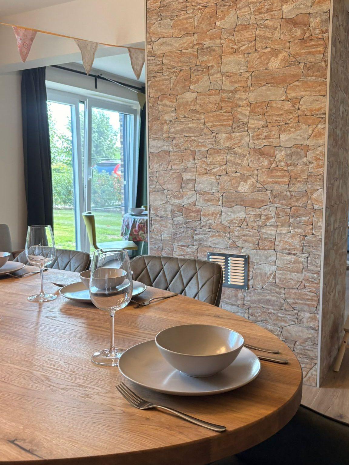 Gedekte eettafel voor acht naast de natuurstenen muur, vakantiewoning Maison Campagnard in Teuven