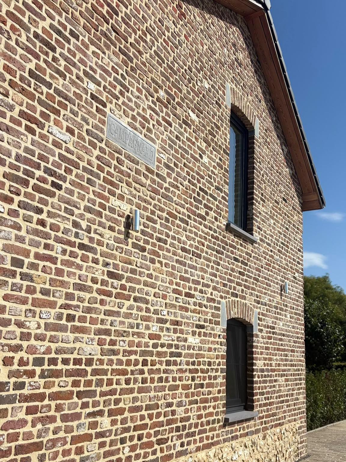 Natuurstenen gevelsteen met de naam Campagnard in het herstelde metselwerk van de vakantiewoning in Teuven