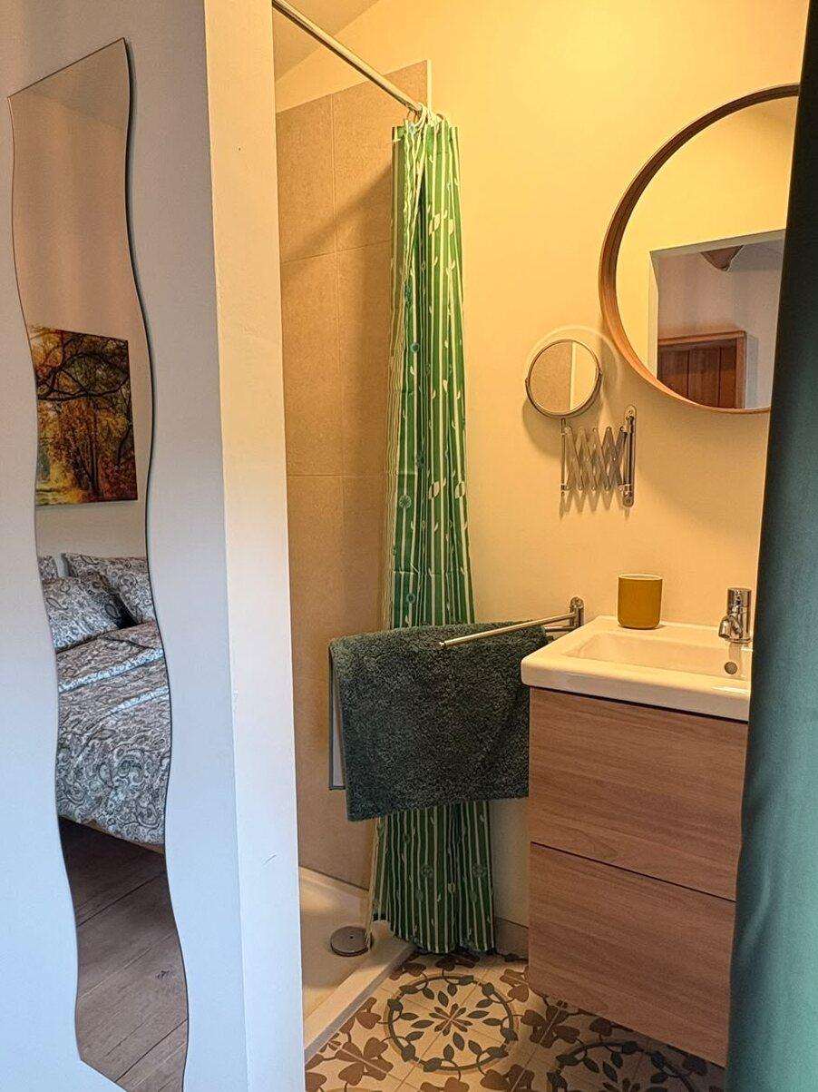Douche et lavabo privés avec miroir rond et carreaux de ciment dans une chambre à l'étage, maison de vacances à Teuven