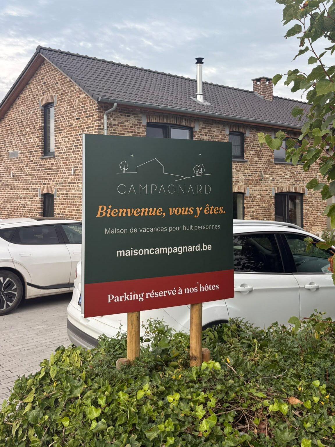 Panneau d'accueil vert de Campagnard avec parking pour les hôtes, devant la ferme rénovée à Teuven